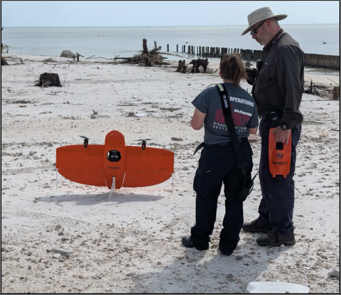 Two people standing on a beach with a drone