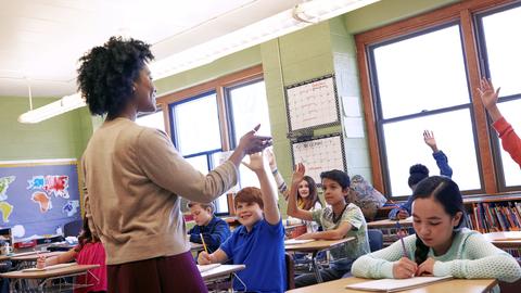 Teacher in front of classroom with young students at desks