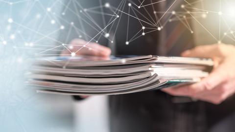 Hands holding magazines and journals with tech web overlay