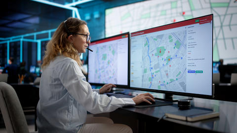 Woman with headset using a computer map to dispatch an ambulance