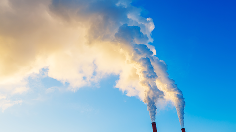 Smoke stacks pouring smoke into a blue sky