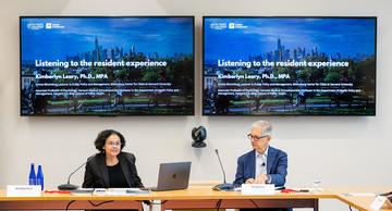 Kim Leary and Stephen Goldsmith speaking at the head of a conference room