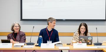 Attendees at a conference table laughing
