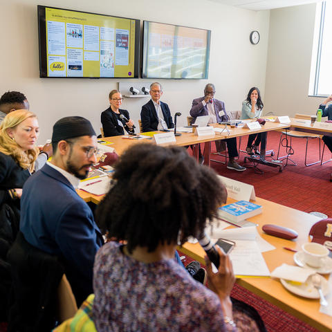 Conference table with people speaking to each other and Stephen Goldsmith at the head