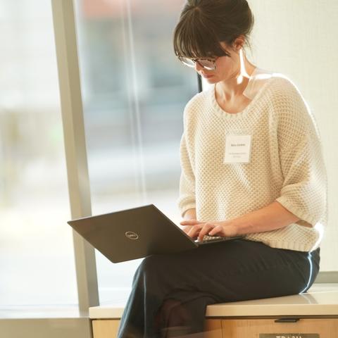 White woman with brown hair typing on a laptop