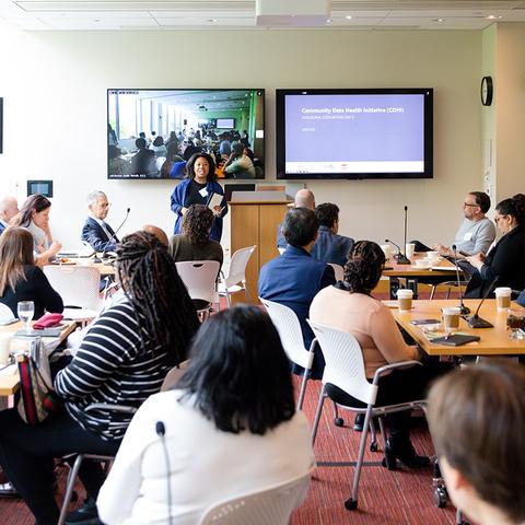A large group of people watching a presentation at the front of a conference
