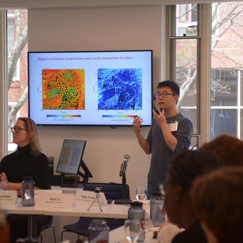 An Asian man and White woman at front of meeting presenting a powerpoint
