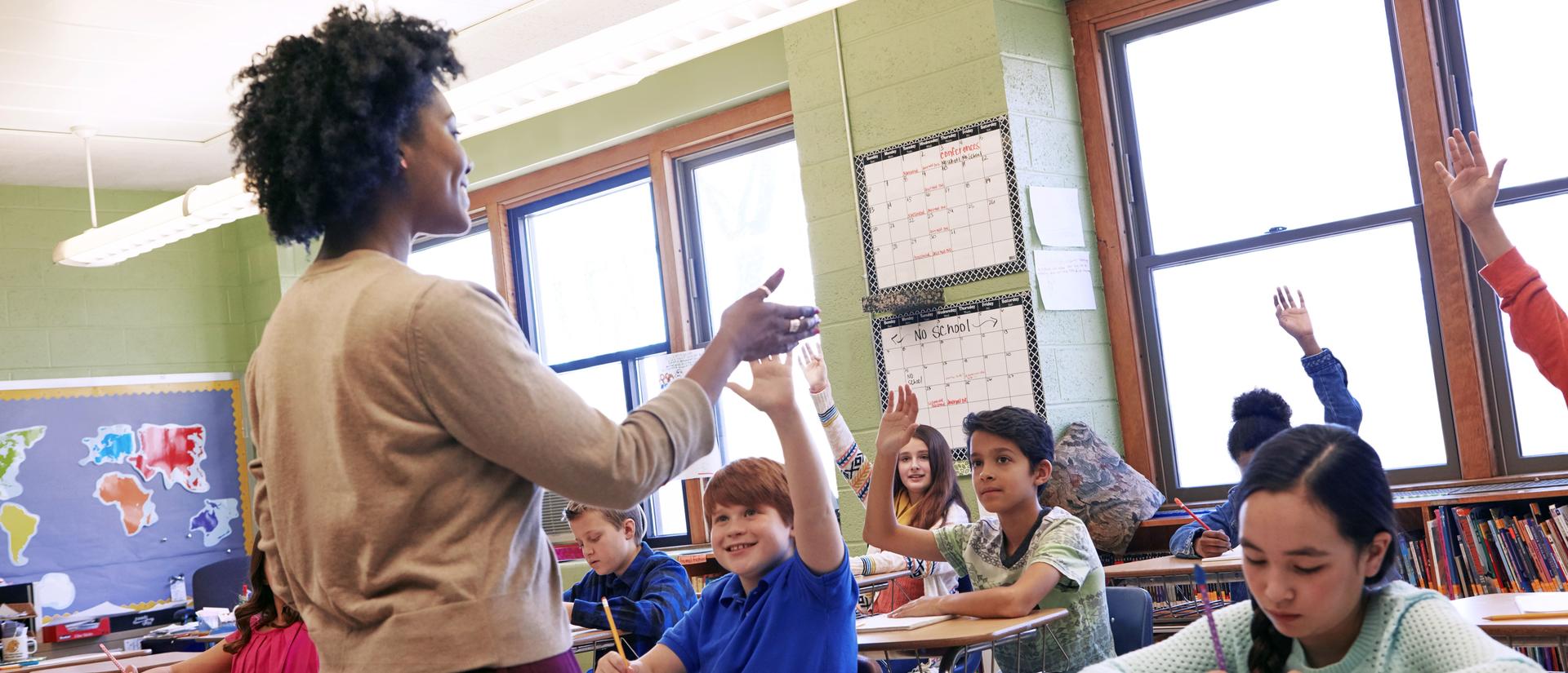 Teacher in front of classroom with young students at desks