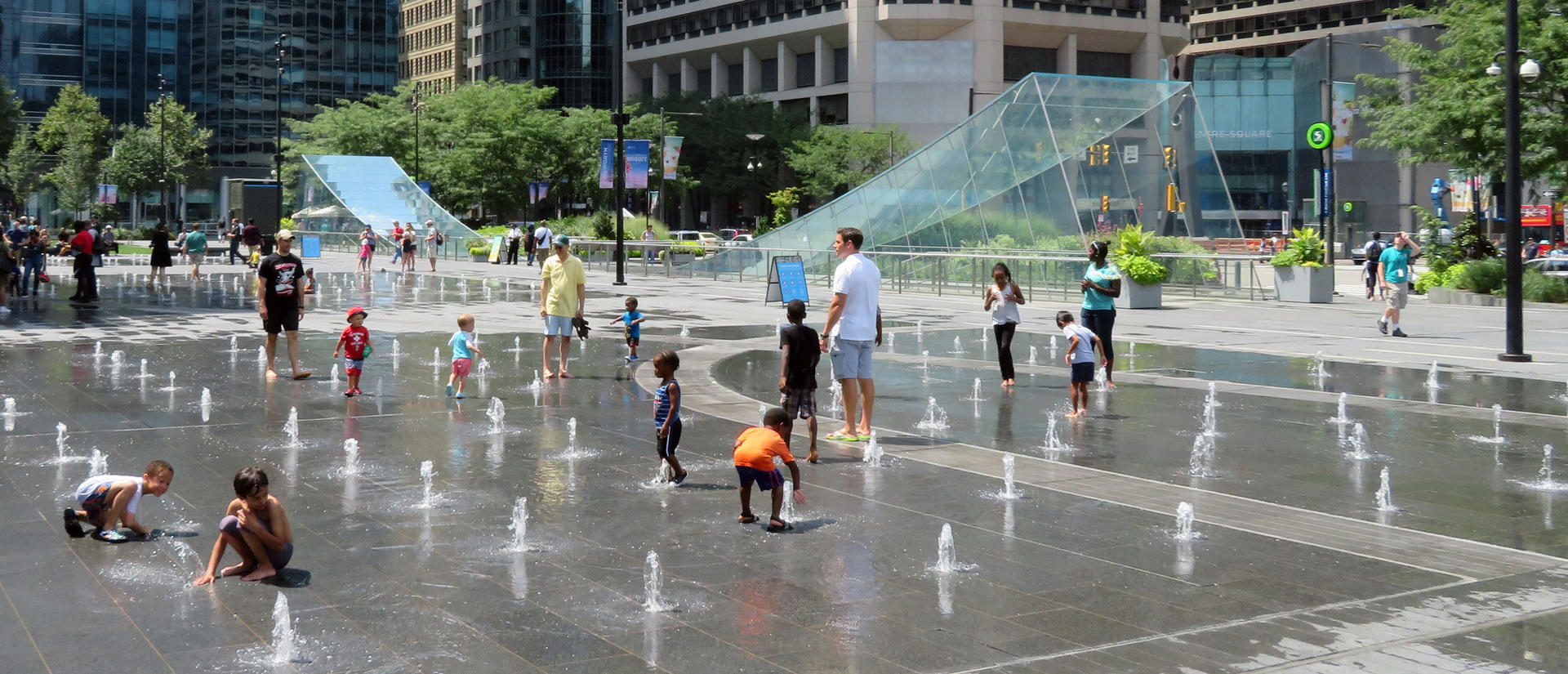 Kids and families playing in water fountains in city plaza