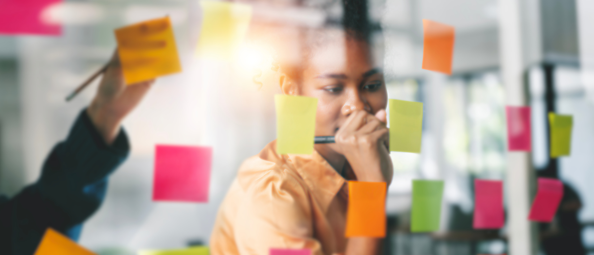 Woman righting on a wall of post-it notes