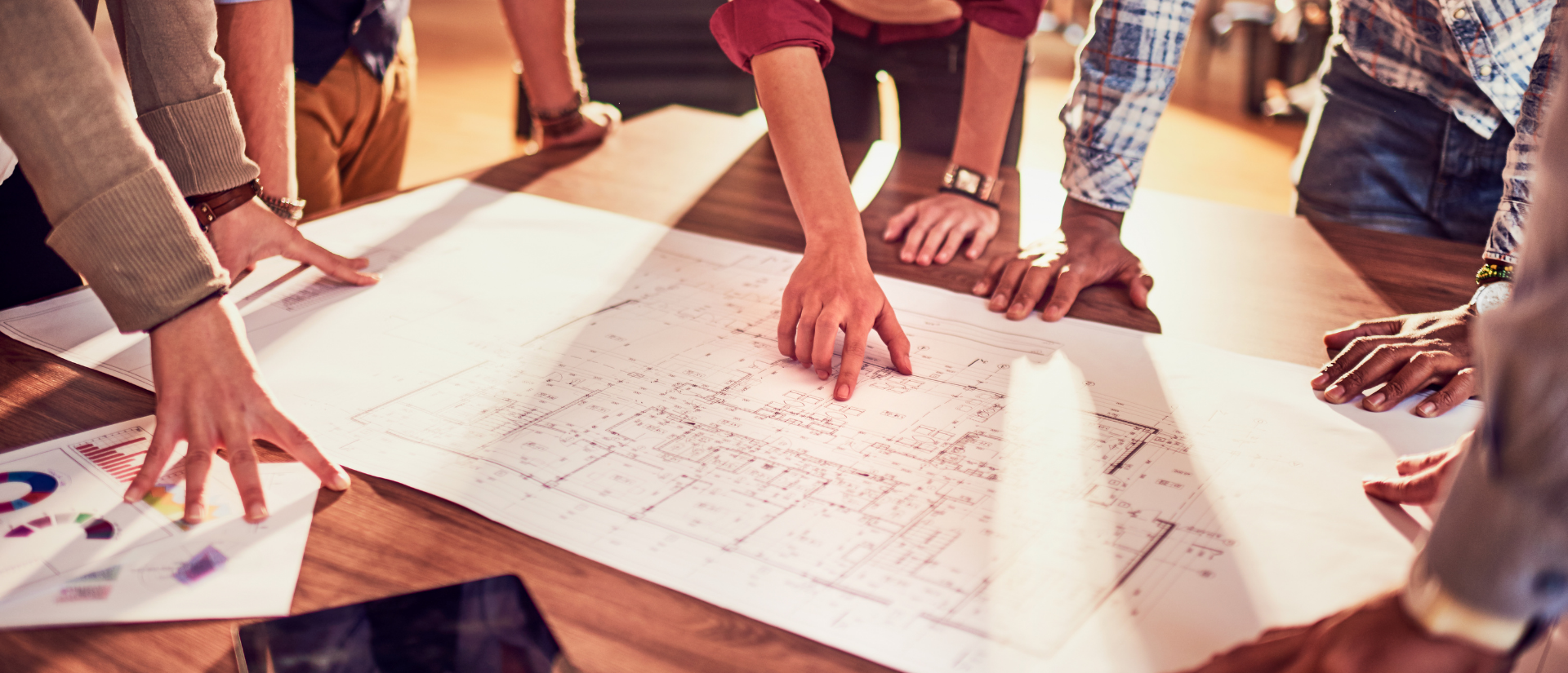 People bent over a desk discussing blueprint plans