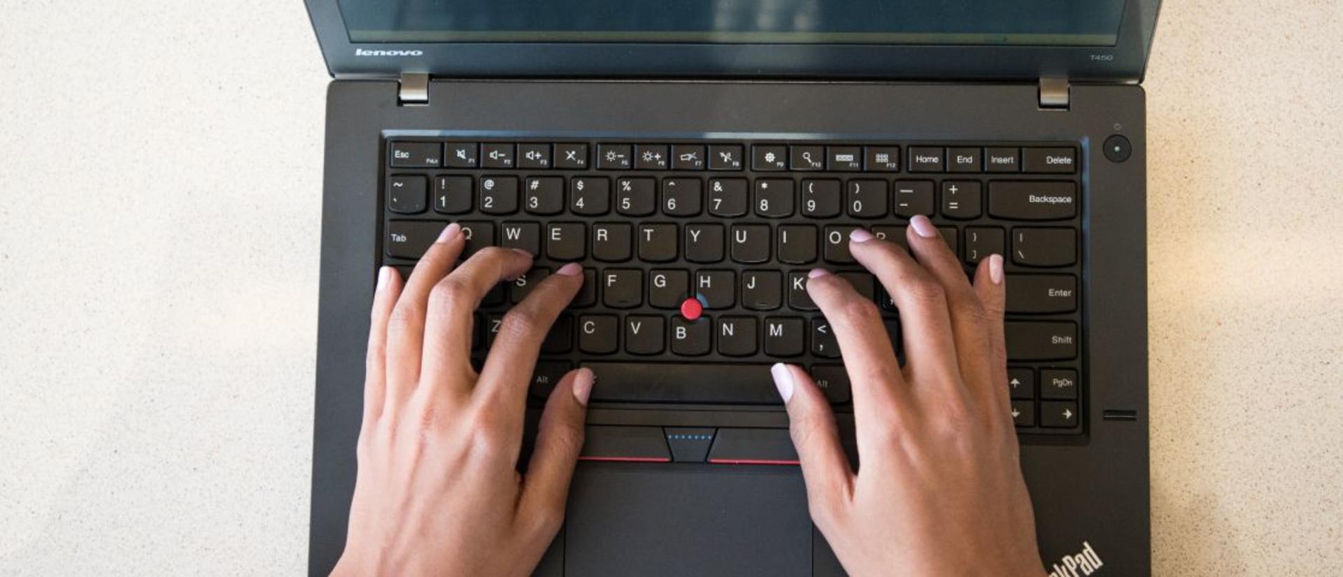 Hands typing on a laptop