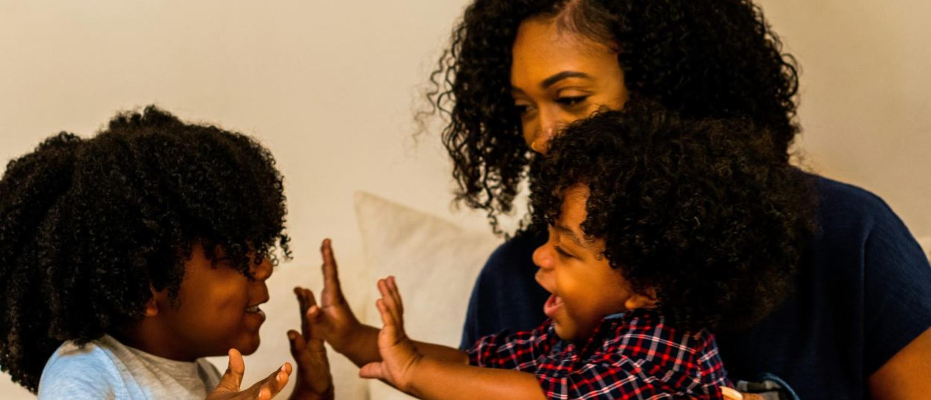 A Black family with mom and two children playing
