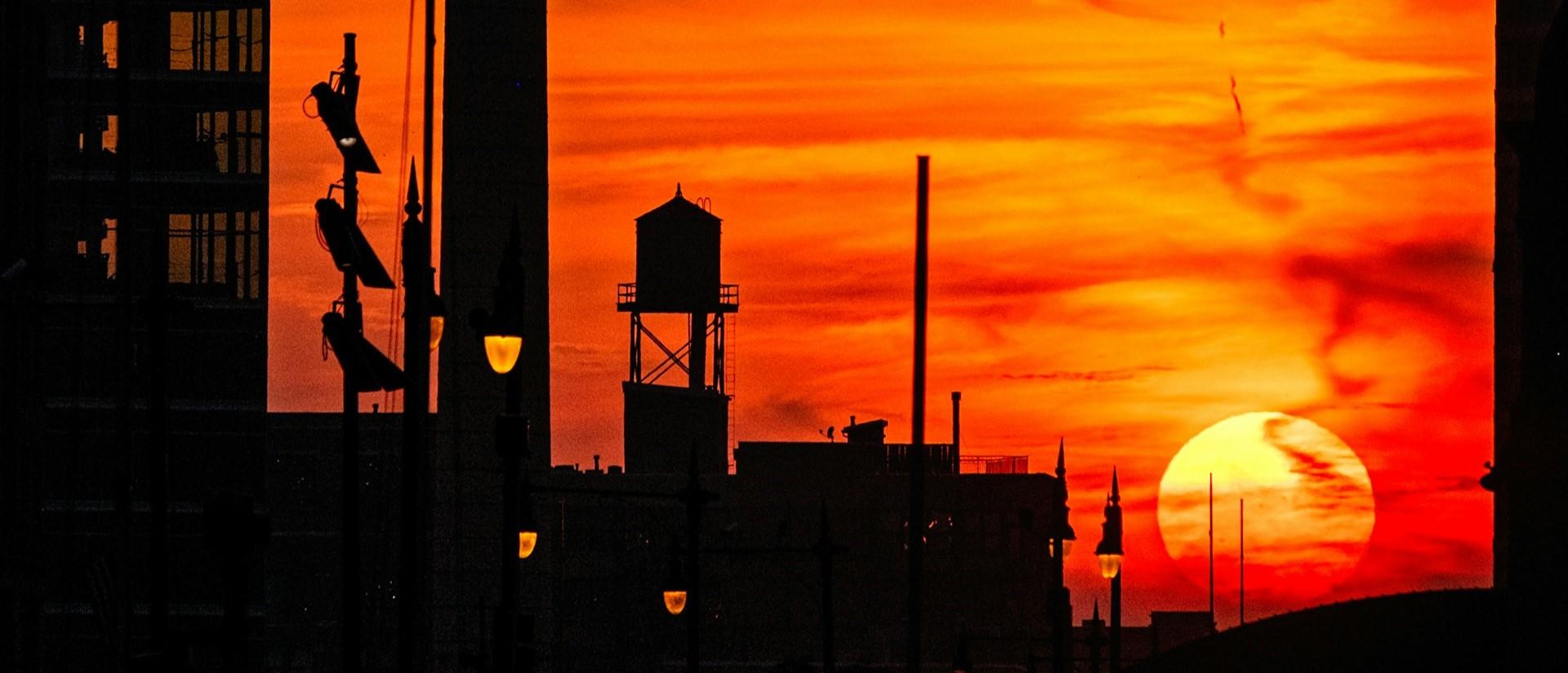 Bright orange sunset behind city buildings