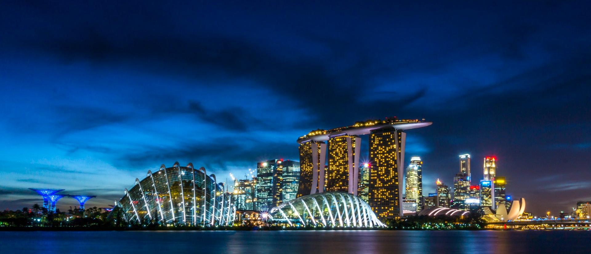 City buildings at night seen from across the water with lights reflecting
