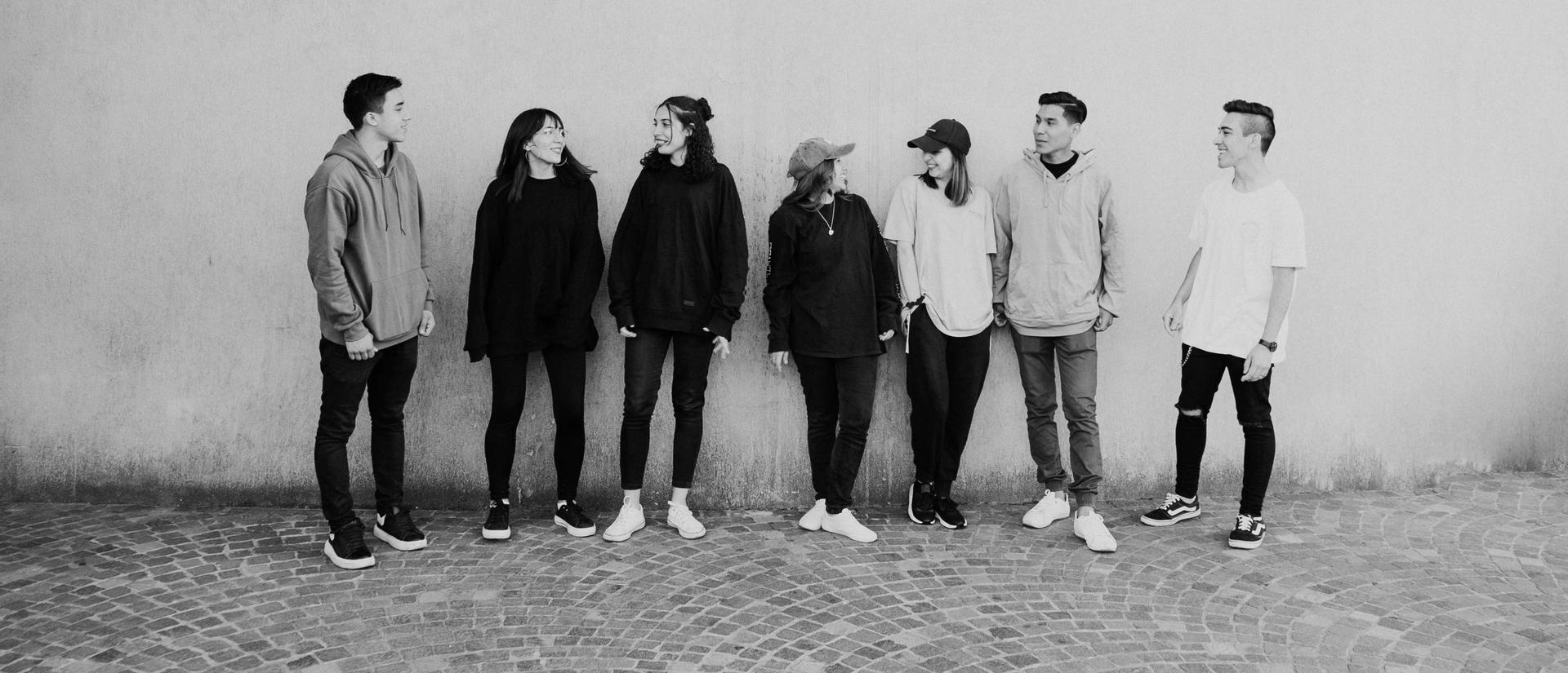 Black and white photo of people hanging out in front of a brick wall