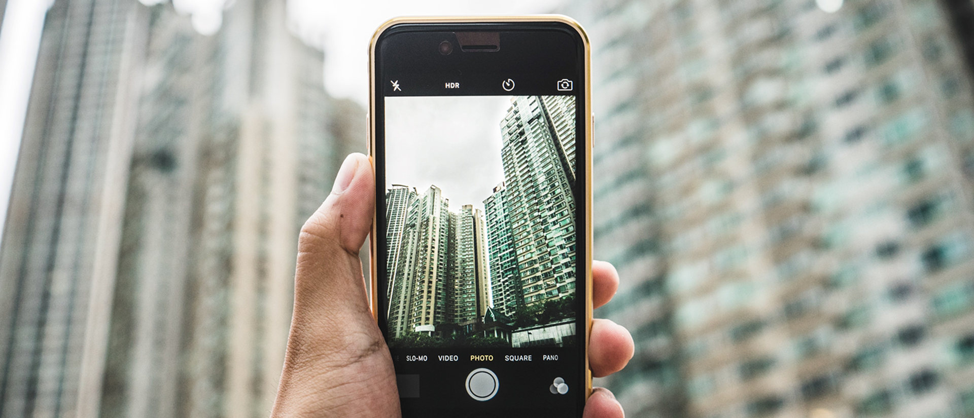 person holding up smartphone with picture of city buildings