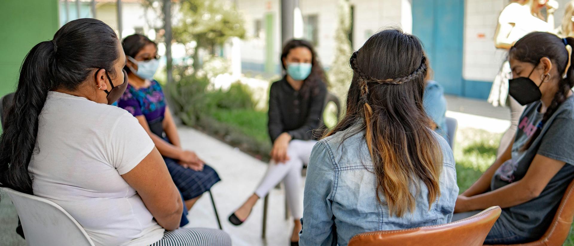 Group of women wearing masks and sitting in a circle outside