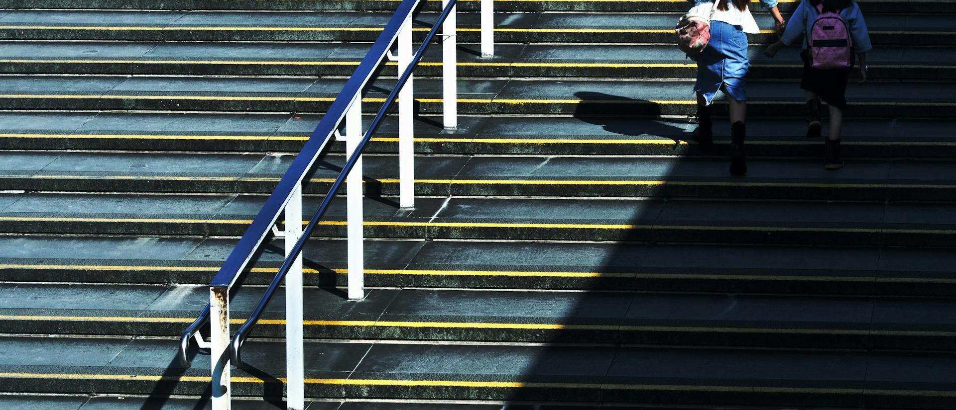 Big outdoor stairwell cast in shade with a parent and child walking up